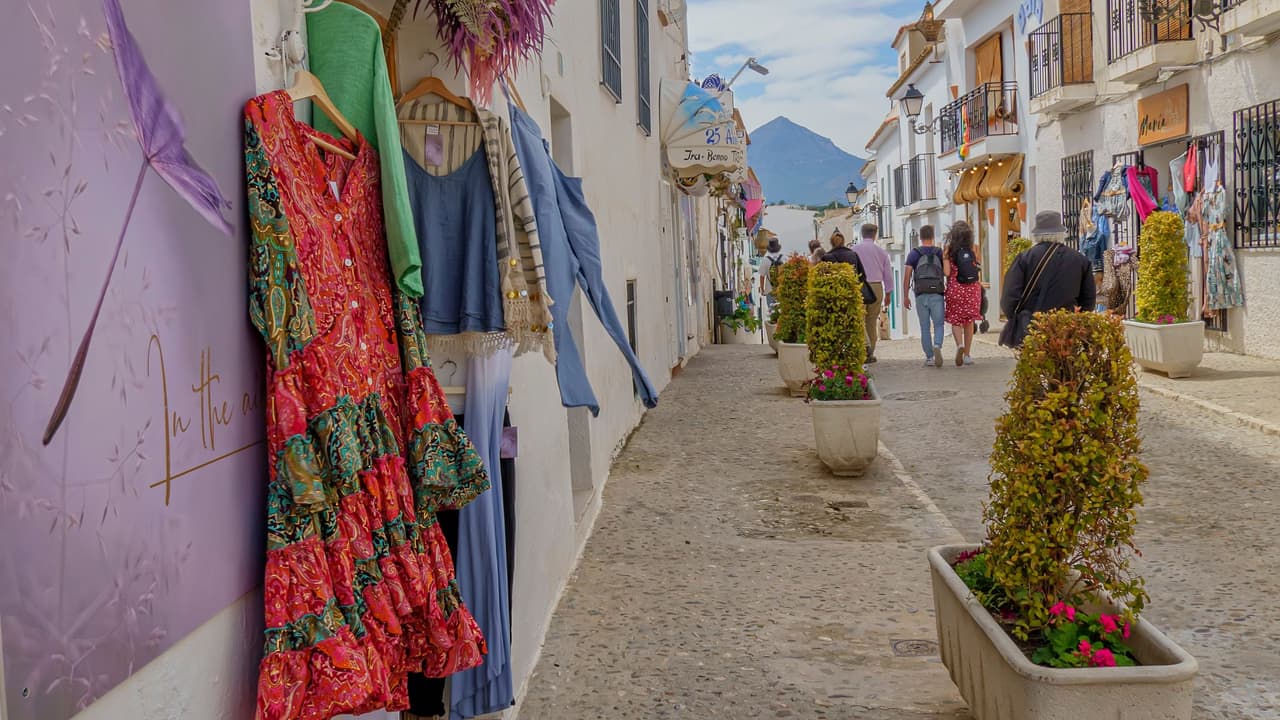 Calle comercial del casco antiguo de Altea con tiendas, macetas y viandantes