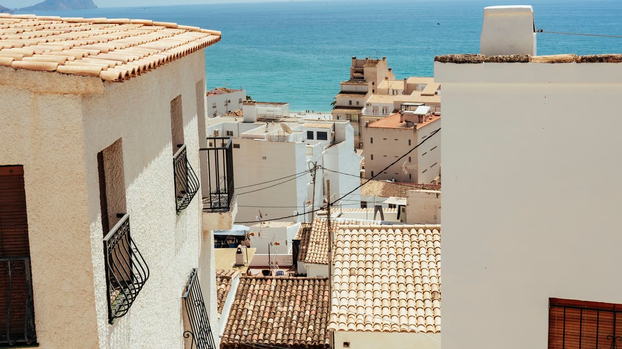 Fachadas encaladas y tejados de teja del casco antiguo de Altea con el mar al fondo