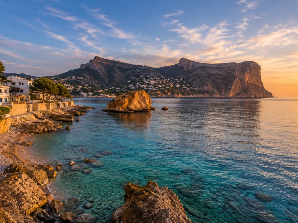 Cala rocosa de la costa norte de Altea al atardecer, con agua turquesa y el acantilado al fondo